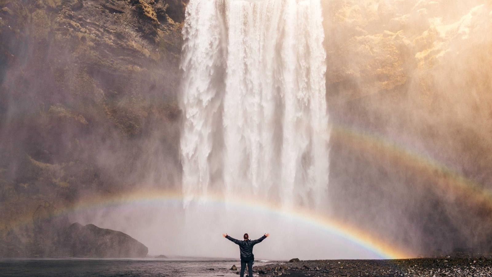 Traveler before a waterfall with rainbow